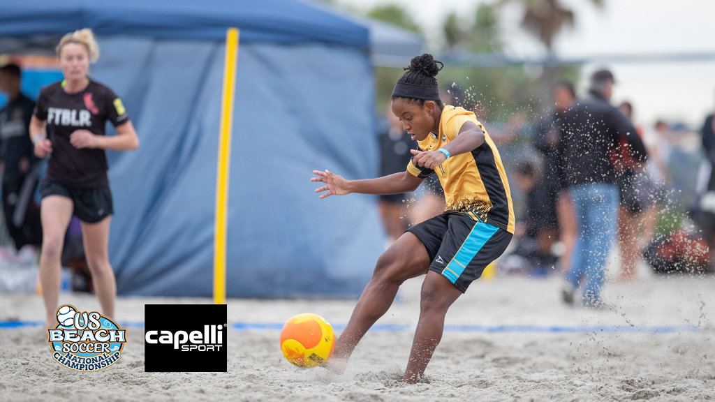 Beach soccer player kicking a soccer ball in the sand